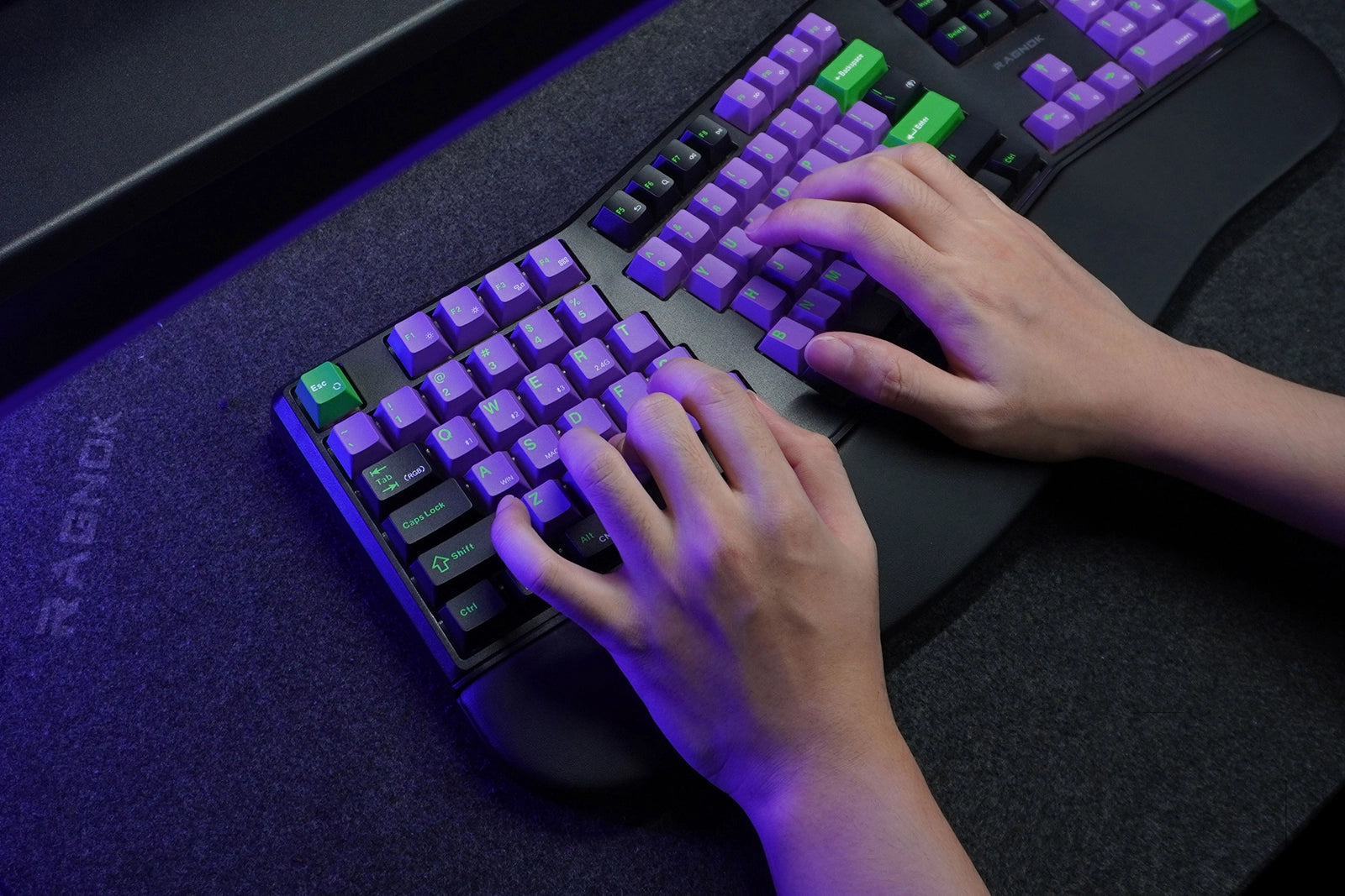 Person typing on a Razer mechanical keyboard with RGB lighting on a dark surface.